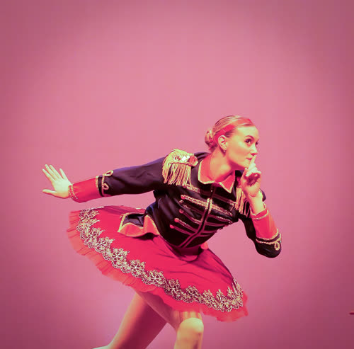 A dancer moving across a pink stage